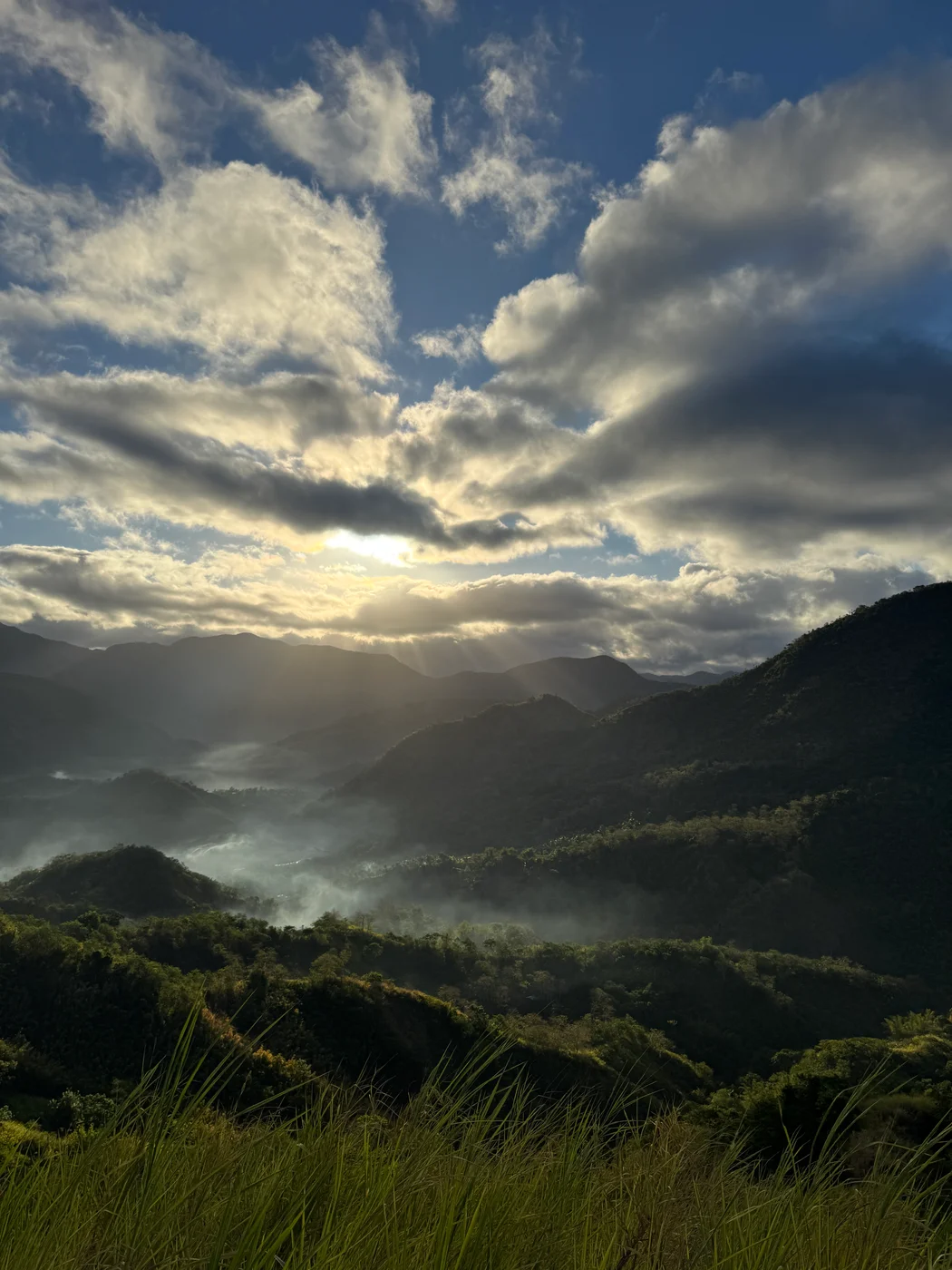 Sunlight breaking through clouds over a mountain valley