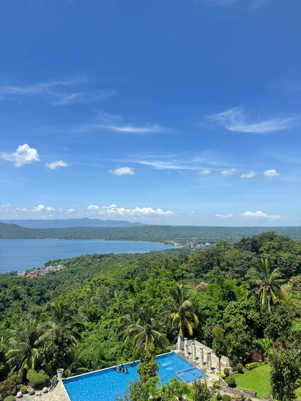 A wide coastal view over green trees and blue water
